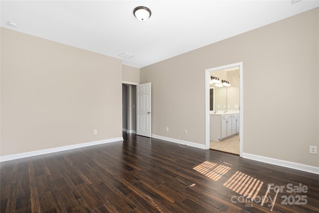 unfurnished bedroom with ensuite bath, baseboards, and wood finished floors