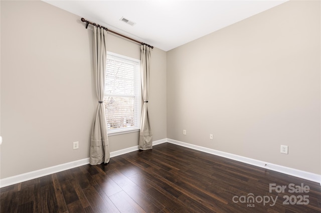 unfurnished room featuring dark wood-style floors, visible vents, and baseboards