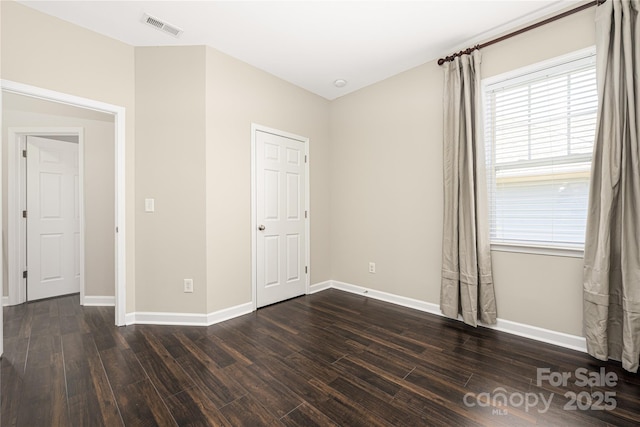 unfurnished bedroom featuring dark wood-type flooring, visible vents, and baseboards