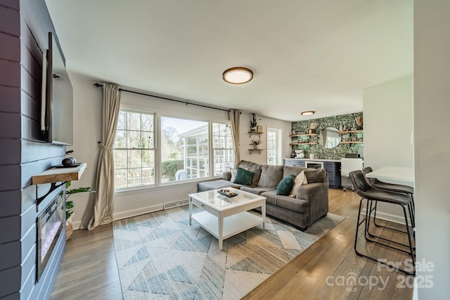 living room featuring visible vents, light wood-style flooring, and baseboards