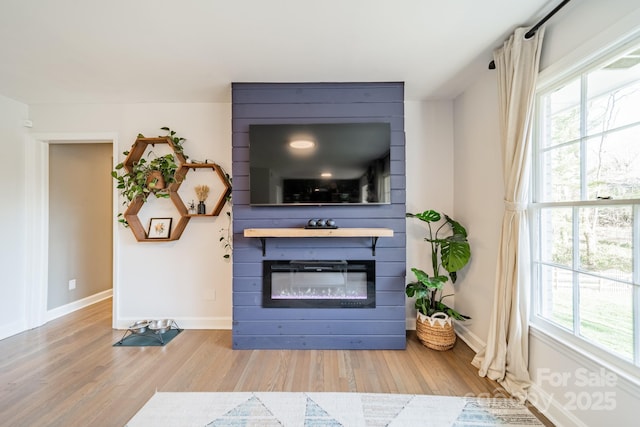 living room with a wealth of natural light, a fireplace, baseboards, and wood finished floors