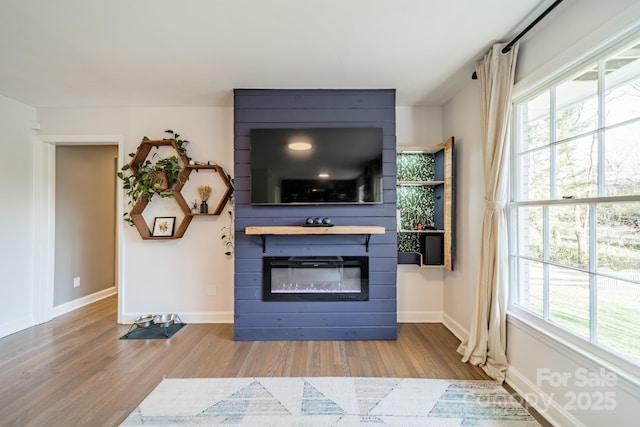 living area with a large fireplace, baseboards, and wood finished floors