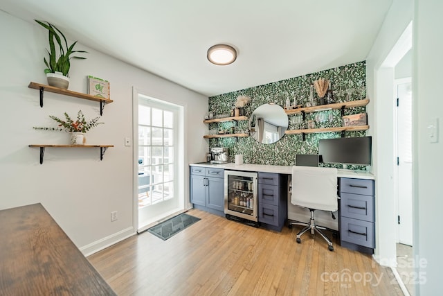 bar featuring wine cooler, backsplash, light wood-style flooring, and baseboards