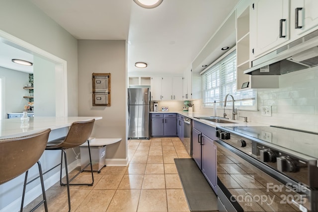 kitchen featuring appliances with stainless steel finishes, a sink, light countertops, white cabinetry, and backsplash