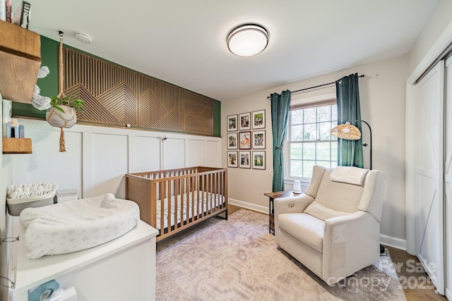 bedroom featuring a nursery area, a closet, and baseboards