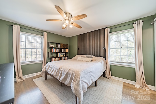 bedroom with a ceiling fan, visible vents, light wood-style flooring, and baseboards