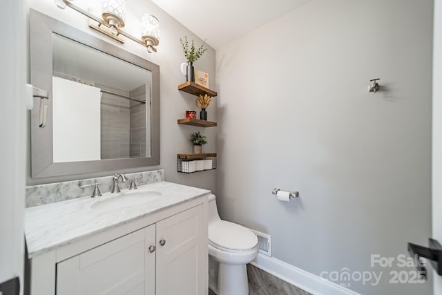 bathroom with visible vents, toilet, vanity, wood finished floors, and walk in shower