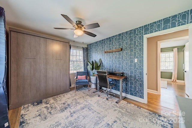 home office featuring wood finished floors, plenty of natural light, baseboards, and wallpapered walls