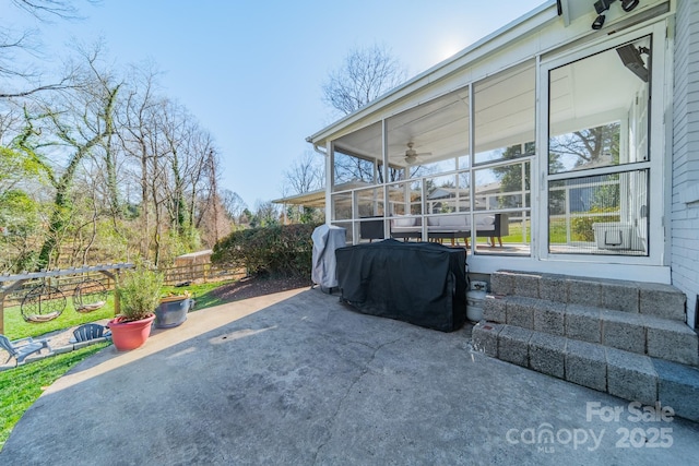 view of patio / terrace with area for grilling, fence, and a sunroom