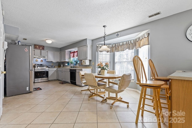 dining space featuring baseboards, visible vents, a textured ceiling, and light tile patterned flooring