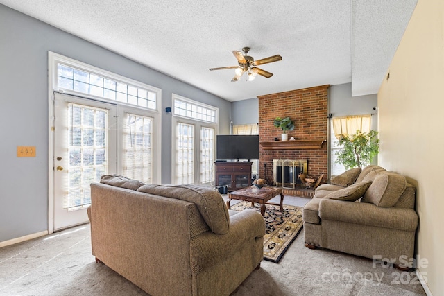 living room featuring light colored carpet, a brick fireplace, ceiling fan, a textured ceiling, and baseboards