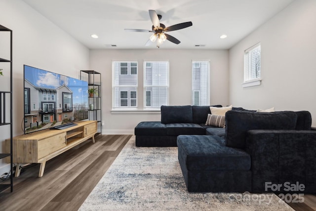 living area featuring visible vents, baseboards, and wood finished floors