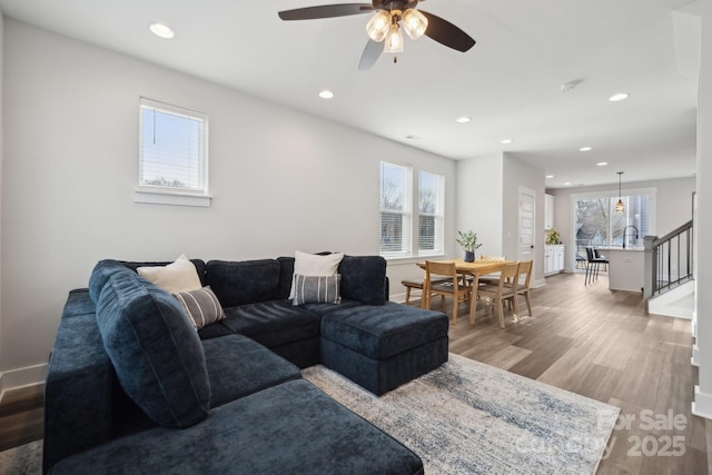 living area with light wood-type flooring, baseboards, stairway, and recessed lighting