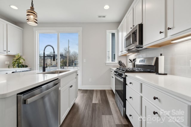 kitchen featuring appliances with stainless steel finishes, a sink, white cabinetry, and decorative backsplash