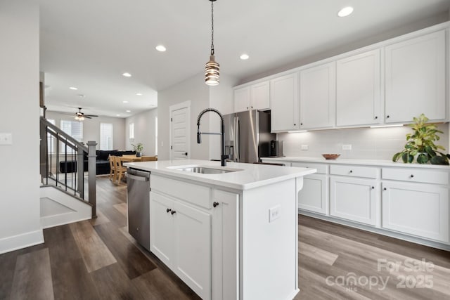 kitchen featuring dark wood finished floors, light countertops, appliances with stainless steel finishes, white cabinetry, and a sink