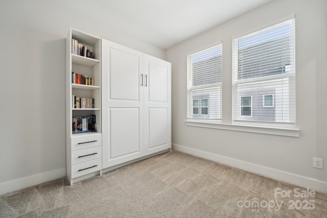 unfurnished bedroom with a closet, light colored carpet, and baseboards