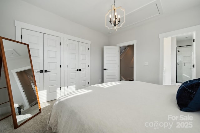 carpeted bedroom with a chandelier, ensuite bath, and two closets