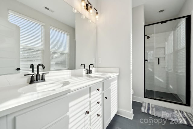 full bath featuring double vanity, a shower stall, visible vents, and a sink