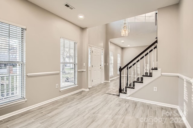 foyer featuring visible vents, stairway, baseboards, and wood finished floors