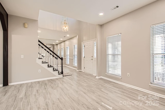 foyer entrance with stairs, visible vents, plenty of natural light, and wood finished floors