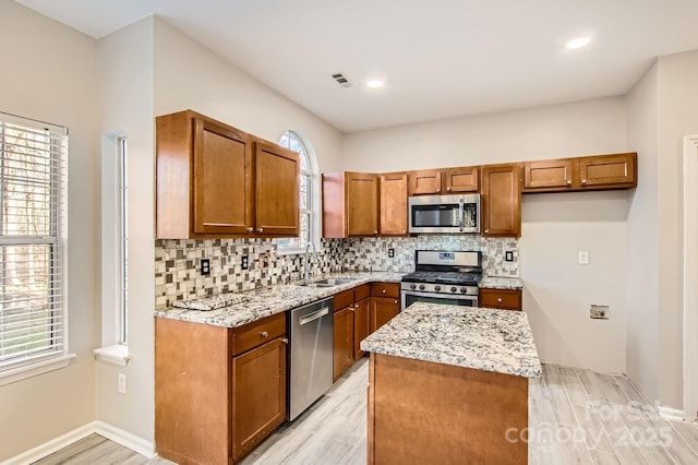 kitchen featuring visible vents, backsplash, appliances with stainless steel finishes, brown cabinetry, and a sink