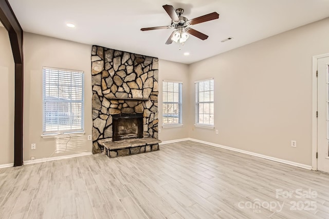 unfurnished living room with a wealth of natural light, visible vents, a fireplace, and wood finished floors