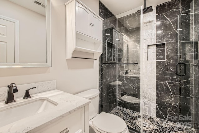 bathroom with toilet, a marble finish shower, visible vents, and vanity