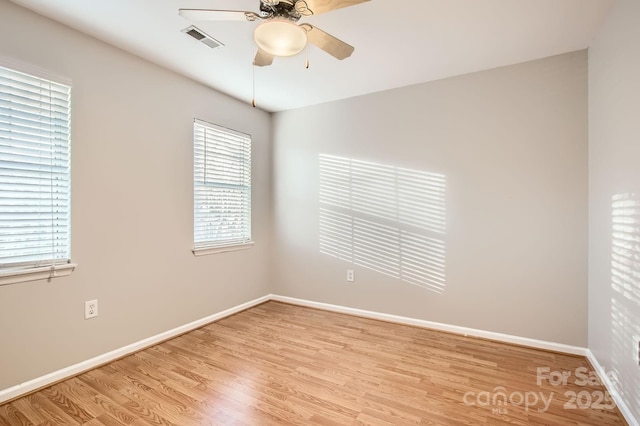 spare room with baseboards, light wood-style flooring, visible vents, and a ceiling fan