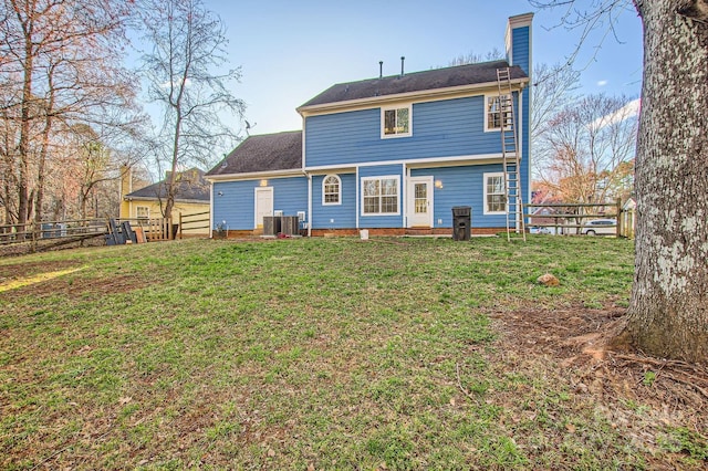 back of house featuring a chimney, fence, and a yard