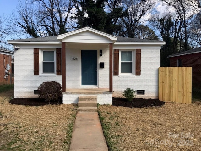 bungalow-style house featuring brick siding, crawl space, and fence