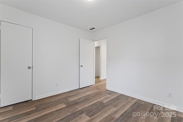 unfurnished bedroom with visible vents, baseboards, and wood finished floors