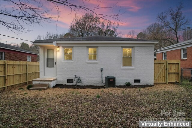 back of house featuring crawl space, a gate, fence, cooling unit, and brick siding