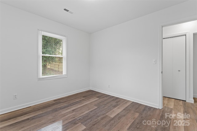 unfurnished bedroom featuring wood finished floors, visible vents, and baseboards