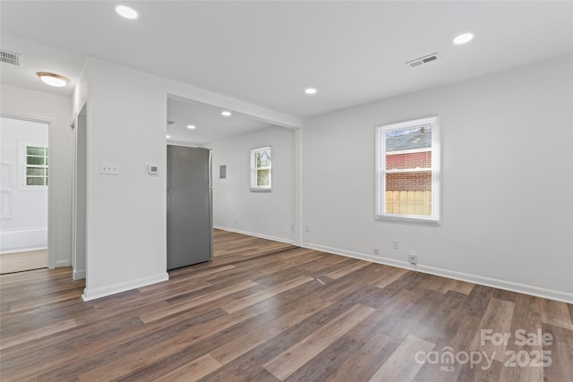 unfurnished room featuring baseboards, visible vents, dark wood finished floors, and recessed lighting