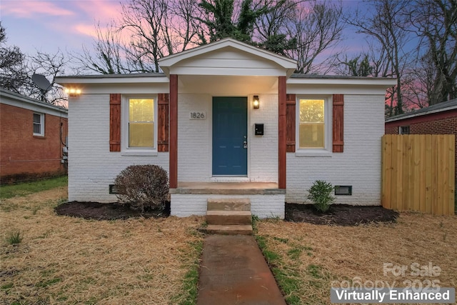 bungalow-style home featuring crawl space, fence, and brick siding