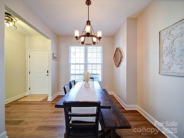 dining room with baseboards, an inviting chandelier, and wood finished floors