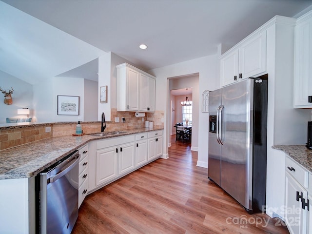 kitchen featuring a sink, white cabinets, appliances with stainless steel finishes, backsplash, and light wood finished floors