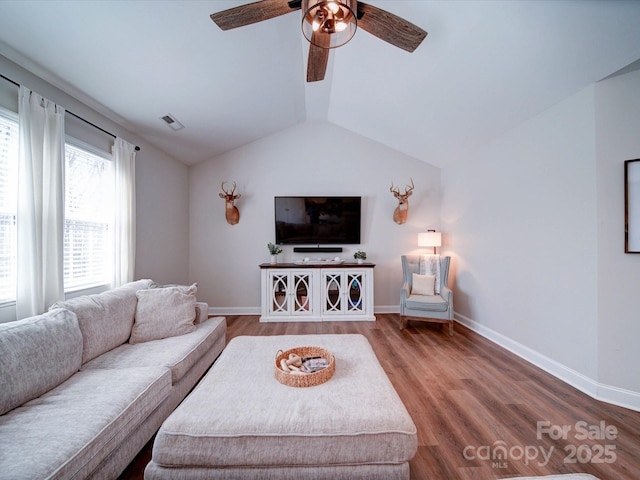 living room featuring baseboards, visible vents, vaulted ceiling, and wood finished floors