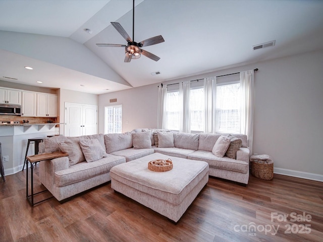 living area featuring baseboards, visible vents, vaulted ceiling, and dark wood-type flooring