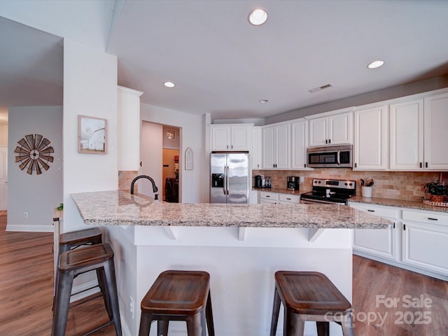 kitchen featuring appliances with stainless steel finishes, backsplash, and a breakfast bar area