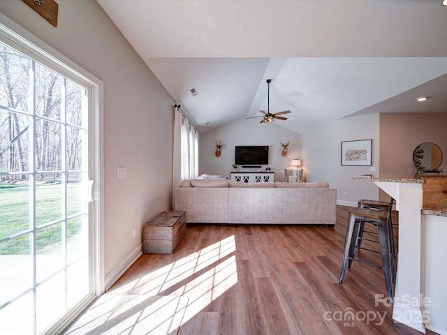 living room featuring baseboards, visible vents, ceiling fan, wood finished floors, and vaulted ceiling