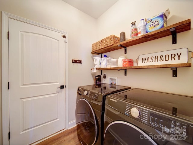 clothes washing area with laundry area, washing machine and dryer, and wood finished floors