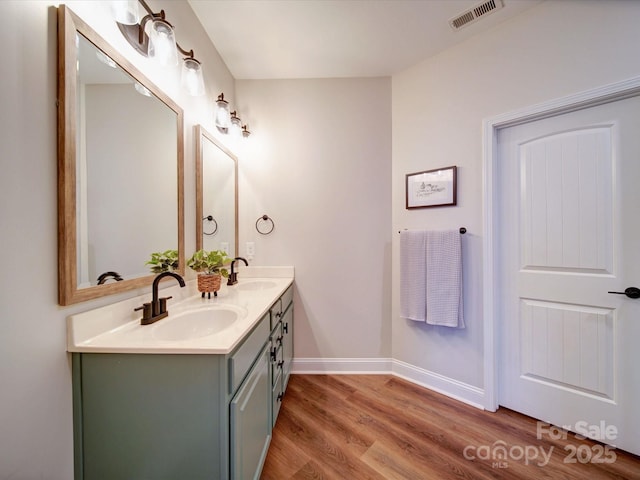 full bath featuring double vanity, visible vents, a sink, and wood finished floors