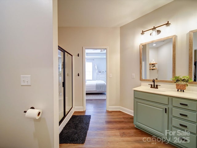 ensuite bathroom with baseboards, wood finished floors, ensuite bathroom, vanity, and a shower stall