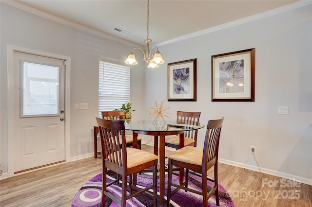 dining space with visible vents, crown molding, light wood finished floors, and an inviting chandelier