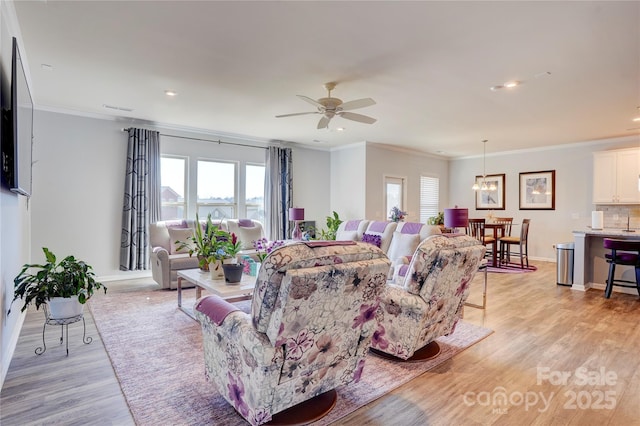 living area featuring a healthy amount of sunlight, light wood finished floors, baseboards, and ornamental molding