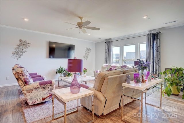 living area featuring visible vents, ornamental molding, ceiling fan, wood finished floors, and baseboards