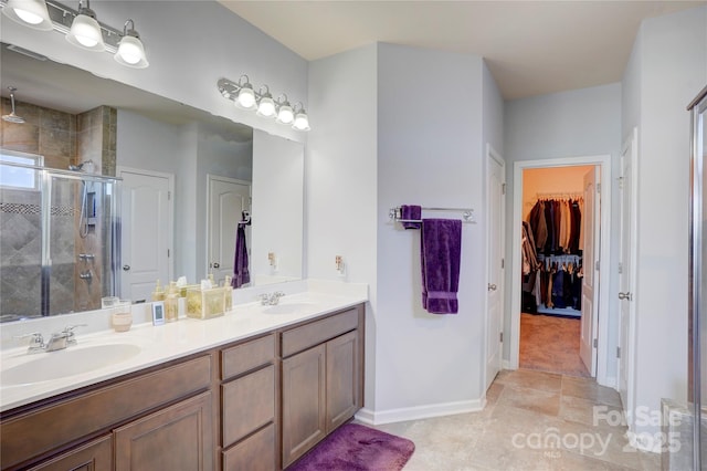 bathroom featuring double vanity, a stall shower, a walk in closet, and a sink