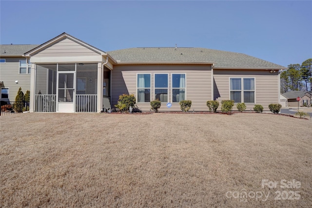 back of house featuring a lawn and a sunroom