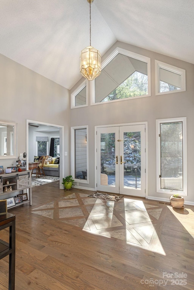 interior space with baseboards, high vaulted ceiling, wood finished floors, and french doors